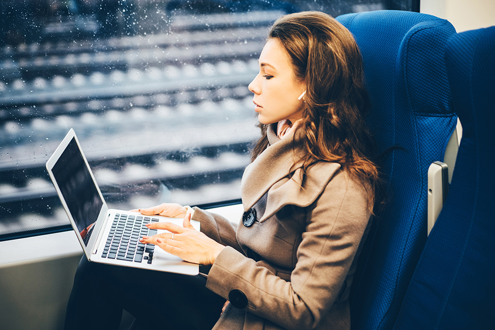 woman commuting on train with laptop
